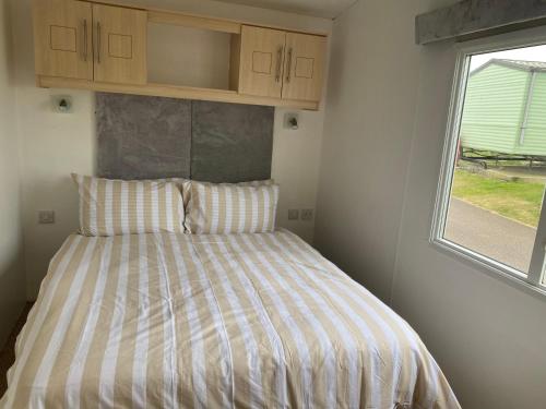 a bed in a small room with a window at ChaletAway in Leysdown-on-Sea