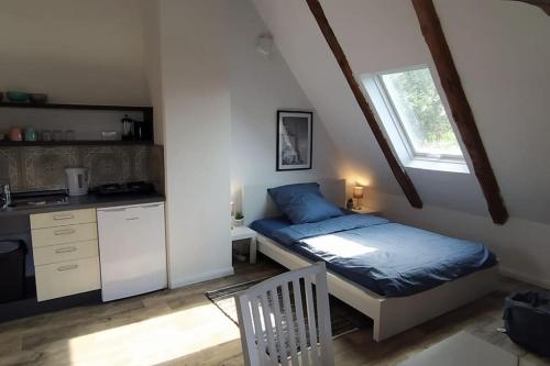 een kleine slaapkamer met een bed en een keuken bij FairSchlafen-Dachstudio in Bücken
