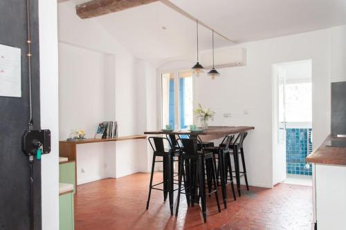 une cuisine avec un bar et des tabourets de bar noirs dans l'établissement Magnifique Duplex proche cours Julien, à Marseille
