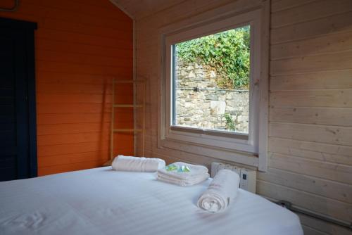 a bed in a room with a window and towels at West Wicklow Glamping with Hot Tub in Baltinglass