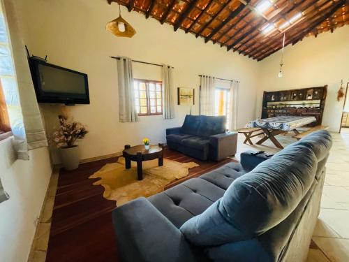 a living room with a blue couch and a tv at Chácara Rancho da Coruja in Itu
