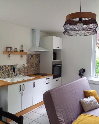 une cuisine avec des placards blancs et un canapé violet dans l'établissement L'écrin de Louise, à Barry-dʼIslemade