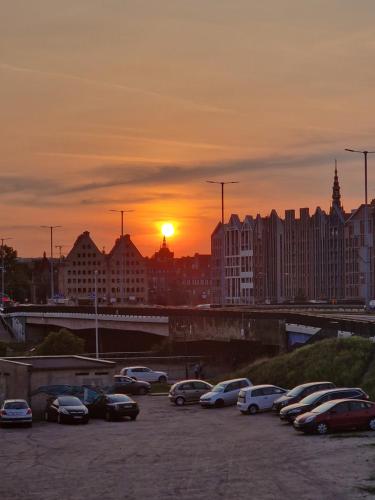 a parking lot with cars parked in front of a sunset at Apartament Zielony in Gdańsk