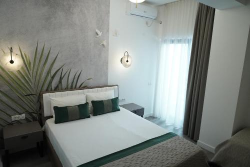 a bedroom with a white bed with green pillows at Denis Boutique in Eforie Nord