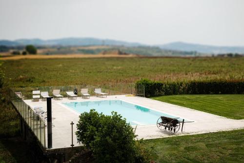a swimming pool in a field with chairs at Country Relais La Torretta Baronale in San Giorgio Montagna