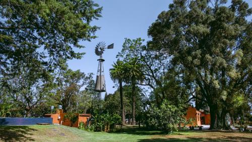 a windmill in the middle of a park with trees at Inti, hospedaje de campo. in Bartolomé Mitre