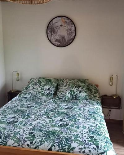 a bedroom with a bed with a green and white comforter at L'écrin de Louise in Barry-dʼIslemade