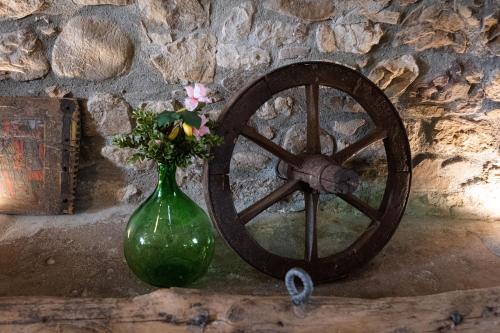 a green vase with flowers sitting next to a wheel at Country Relais La Torretta Baronale in San Giorgio Montagna
