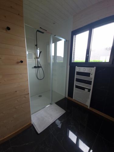 a bathroom with a shower with a window and a window at Le Chalet de St Vigor in Saint-Vigor-le-Grand