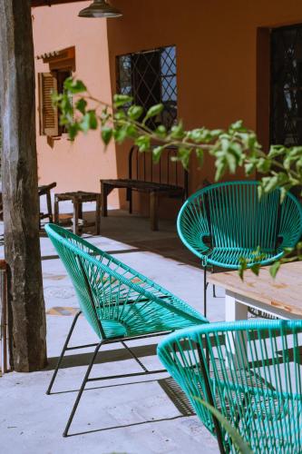 two green chairs sitting on a patio next to a tree at Inti, hospedaje de campo. in Bartolomé Mitre