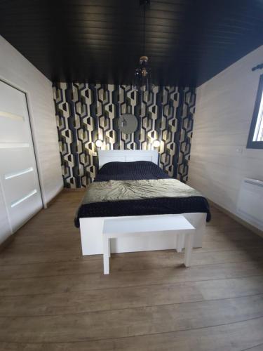- une chambre avec un lit blanc et un mur noir dans l'établissement Le Chalet de St Vigor, à Saint-Vigor-le-Grand