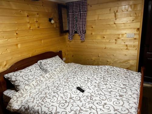 Bett in einem Zimmer mit einer Holzwand in der Unterkunft Krcma u Planini 