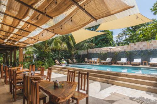 een buitenrestaurant met tafels en stoelen en een zwembad bij Hotel Michanti in El Zonte