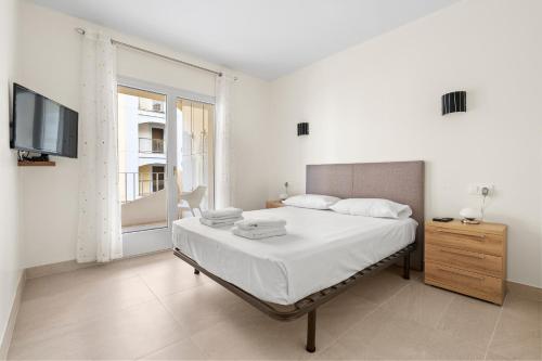 biała sypialnia z łóżkiem i telewizorem w obiekcie Apartamento WELCS EMP 093 con vistas al Canal w mieście Empuriabrava