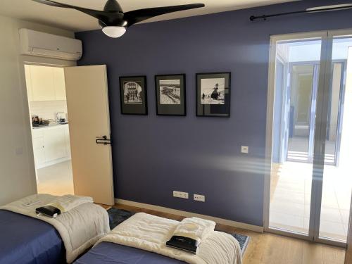 een slaapkamer met een blauwe muur en een plafondventilator bij Picasso Apartament in Tavira