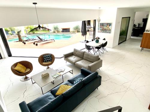 - un salon avec un canapé, une table et une piscine dans l'établissement Villa d’exception Montpellier, à Saint-Jean-de-Védas