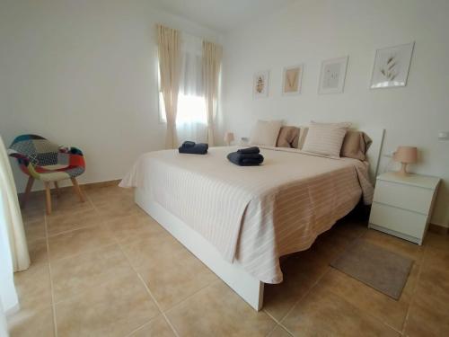 a white bedroom with a bed and a chair at Casa Atlantica Golf & Sea view in Caleta De Fuste