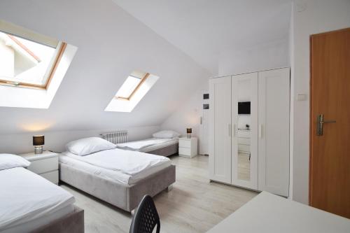 a white bedroom with two beds and a window at U KAZI in Niechorze