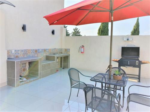 墨西哥城的住宿－S88 SUPER MINI DEPA HERMOSO!!!! A 5 MIN DEL ITES CEM，庭院配有带红色遮阳伞的桌子