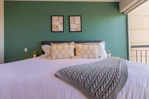 a bedroom with a large white bed with two pictures on the wall at Capitalia - Apartments - Santa Fe in Mexico City