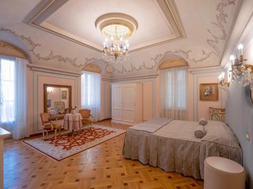 a bedroom with a bed and a table and a chandelier at Casa Balzola - Suite Incanto in Alassio