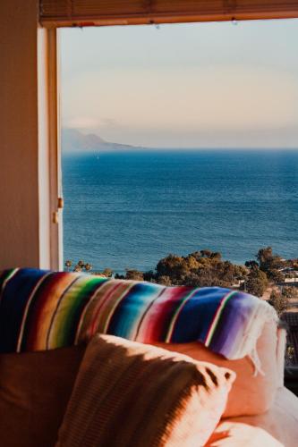 a couch with a view of the ocean from a window at Su Casa in Ensenada