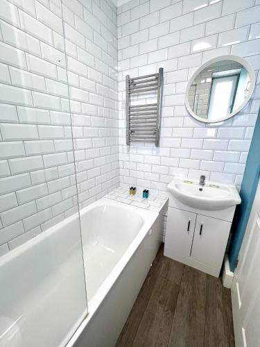 uma casa de banho branca com uma banheira e um lavatório em Modern 2 bed flat close to Shoreditch / Free Wi-Fi em Londres