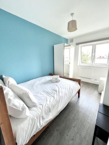 a bedroom with a large bed with a blue wall at Modern 2 bed flat close to Shoreditch / Free Wi-Fi in London