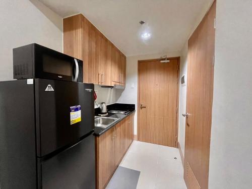 a kitchen with a black refrigerator and a sink at Shore 3 Tower 1 MOA Pasay F Suite Staycation in Manila