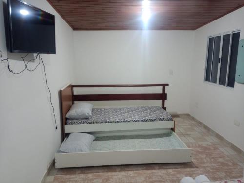 カンポス・ド・ジョルドンにあるCantinho da Saudadeのベッド1台、薄型テレビが備わる客室です。