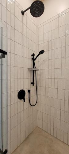 a shower in a white tiled bathroom with a shower head at La Futaie in Saint-Donat-de-Montcalm