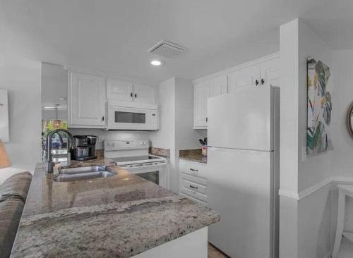 a kitchen with white cabinets and a white refrigerator at Sugar Sands-Luxury 1st Floor 2BR 2BA Private Beach in Gulf Shores