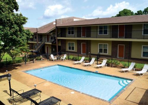 a swimming pool in front of a building with chairs and a house at Summer Getaway in Fondren! Sleeps 6 with pool Access! in Jackson