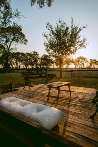 a wooden deck with a picnic table and a bench at Inti, hospedaje de campo. in Bartolomé Mitre