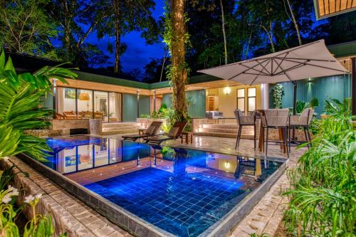 an outdoor pool with a table and an umbrella at The Oasis at Puket in Manzanillo