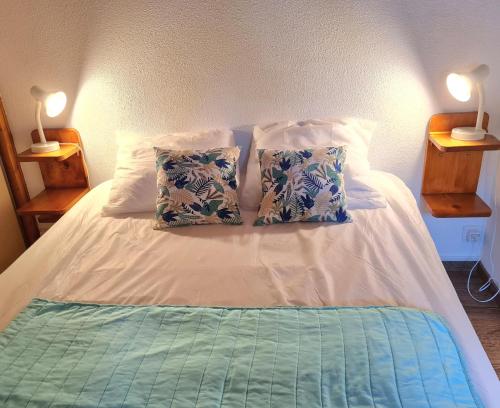 - un lit avec 2 oreillers et 2 lampes dans l'établissement Résidence avec piscine , Talaris à La Palmyre, aux Mathes