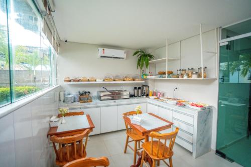 a kitchen with a table and chairs and a counter at Pousada Antonella in Maragogi