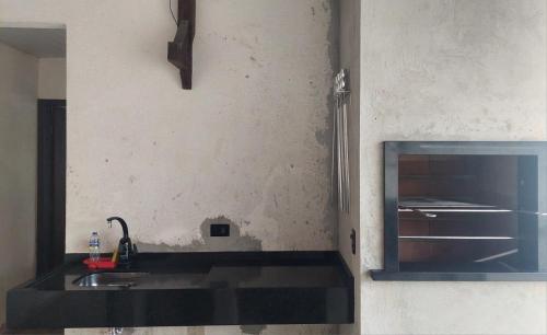 uma cozinha com um lavatório preto e um espelho em Casa Aconchego - piscina com hidromassagem em Guaratuba