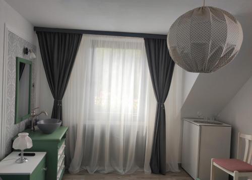 a bathroom with a window with curtains and a chandelier at Mosel Boutique in Bruttig-Fankel