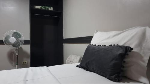 a white bed with a black pillow and a fan at Hotel Asturias in Viña del Mar