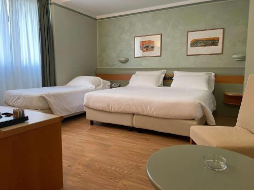 a hotel room with two beds and a couch at Best Western Hotel Leonardo da Vinci in Erba