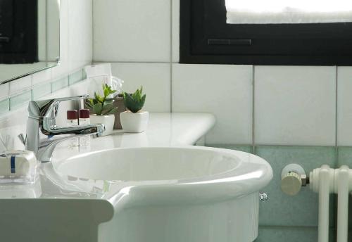 a white bathroom with a sink and a mirror at Hotel Leonardo da Vinci in Erba