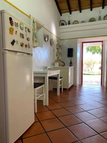 a kitchen with a white refrigerator and a table at Casa dos Pécoxinhos in Arcos