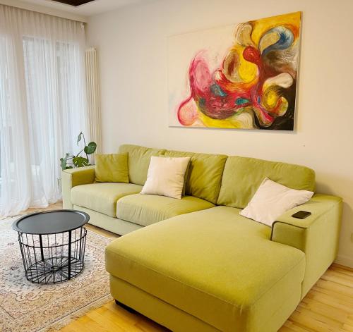 una sala de estar con un sofá verde y una pintura en Prime Comfort Apartment with Balcony & Free Parking, en Berlín