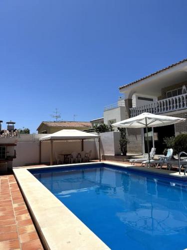 卡萊塔德菲貝萊斯的住宿－Detached Pool Villa, idyllic setting 450m to beach，房屋旁的游泳池配有椅子和遮阳伞