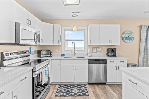 a kitchen with white cabinets and a sink at Blue View in Holden Beach