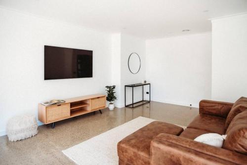 ein Wohnzimmer mit einem Sofa und einem Flachbild-TV in der Unterkunft Leafy Retreat - Benalla in Benalla