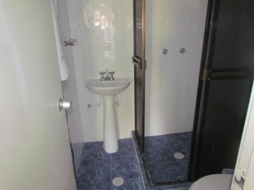 uma casa de banho com um lavatório e um chuveiro em HOTEL DINASTIA REAL NEIVA em Neiva