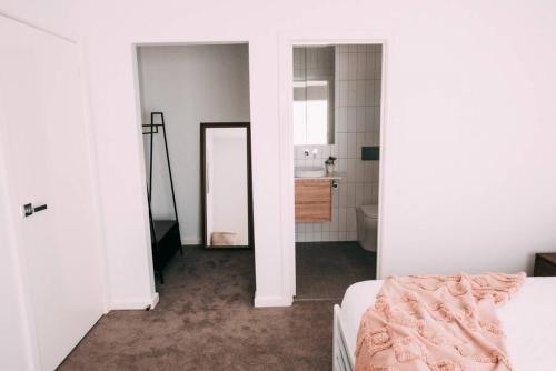 a white room with a bed and a bathroom at The Vine House - Benalla in Benalla