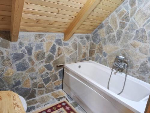 a bathroom with a tub and a stone wall at Brvnara Ibar in Rožaje